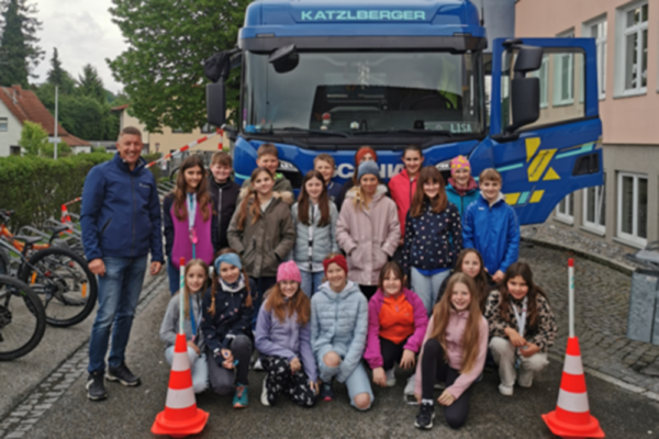 Schüler stehen rund um einen LKW