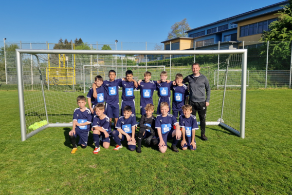 Ein Fußballteam posiert im Fußballtor und lächelt in die Kamera